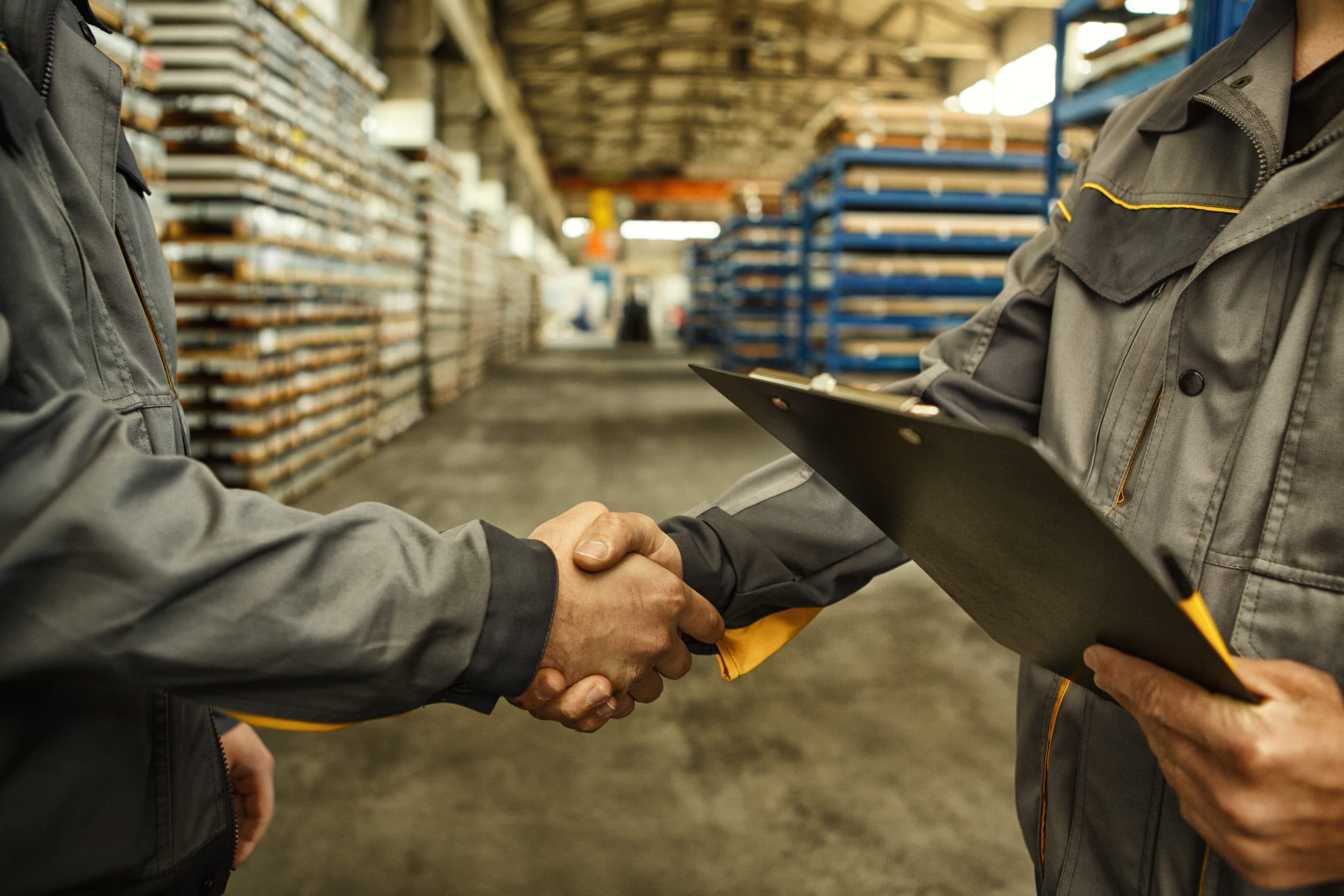 A vendor and program manager shaking hands on a warehouse floor